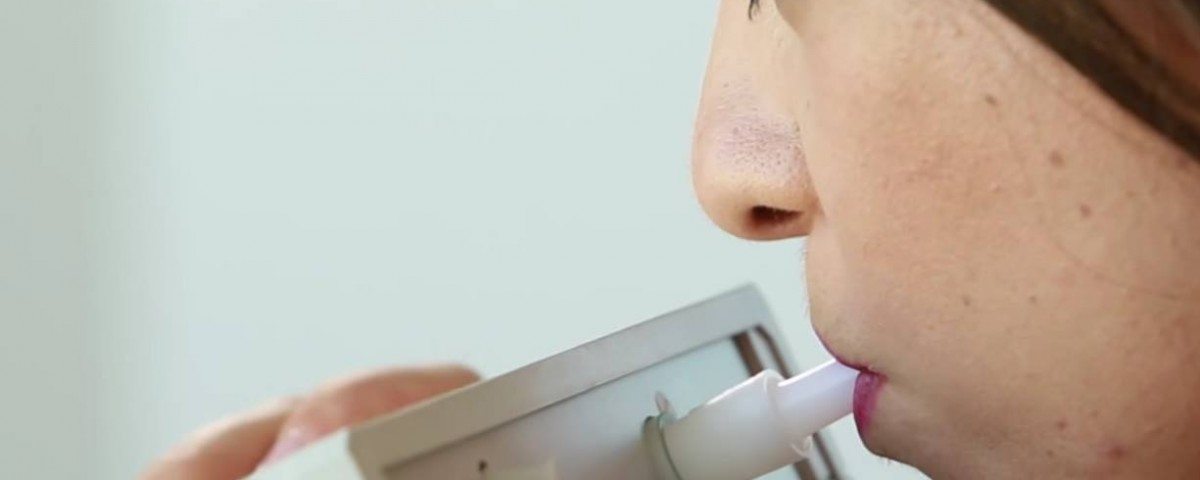 Woman breathing into device that can detect early stages of disease