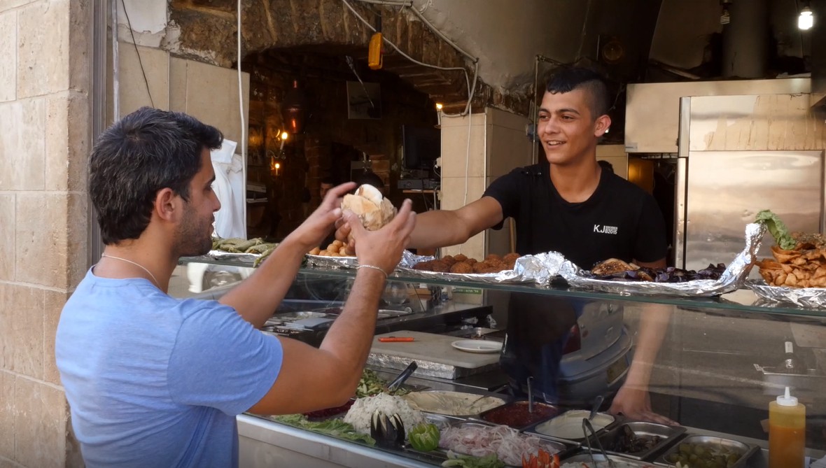 A guy buying falafel in a falafel stand in israel for culinary delight 