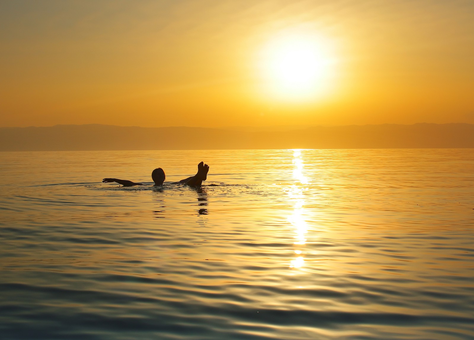 a person floating in the sea during sunset chilling and relaxing