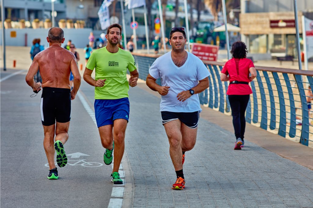two guys running at the tel aviv promonade by the beach showing a post holiday workout