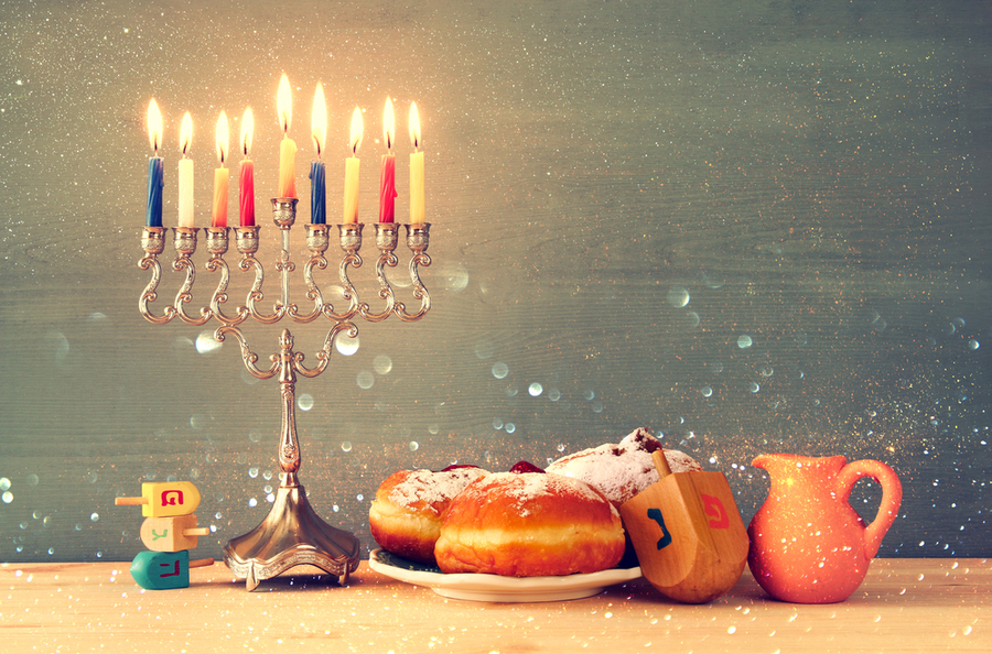 menora, doughnuts, dreidel, and a pitcher of oil all Hanukkah symbols 