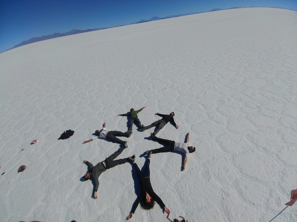 salar de uyuny or salt flats in bolivia where Israeli travelers or backpackers are laying on their backs creating a star on the ground making a cool picture